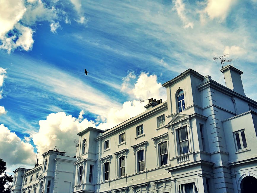 A multi-storey brick building with white window frames and small balconies on the upper floors is situated along a city street. On the pavement directly in front of the building, there are several bic
